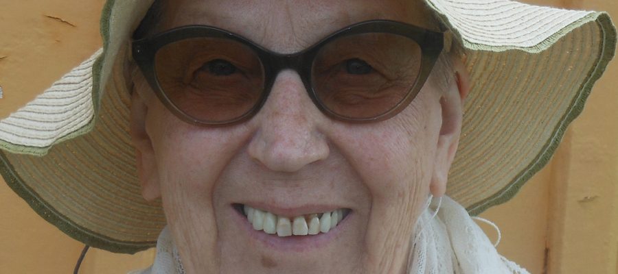 Leende äldre kvinna med glasögon och hatt